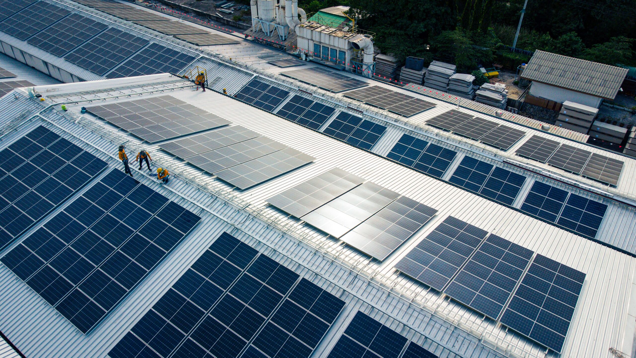 Solar_panels_plant coesa File di pannelli solari in un campo erboso, di fianco ad una strada. Nel cielo un po' di nuvole con il sole che sta tramontando